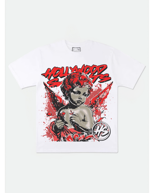 White Hollywood Saints t-shirt with bold red graffiti text and a dramatic cherub graphic featuring red wings, paint splatter effects, and an HS logo emblem. Striking streetwear design with angel and rebel themes.